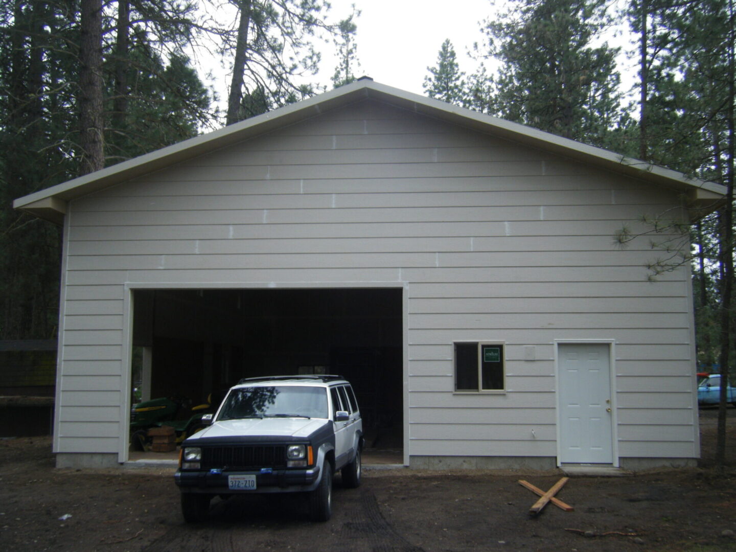 Front view of a light-colored house with a car emerging from the garage
